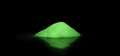 bright neon green glowing mica powder sitting on a black countertop, showcasing how to mix glow in the dark epoxy