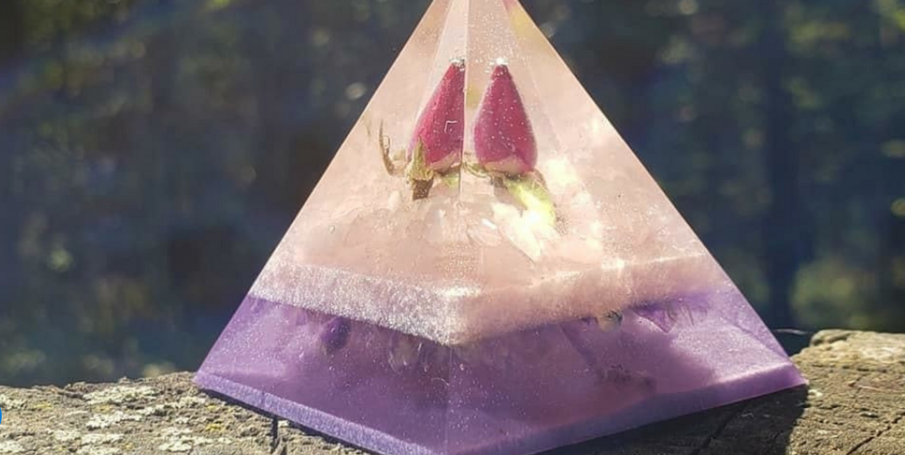 purple and light pink resin pyramid with a strawberry encapsulated inside it sitting on a deck railing outside
