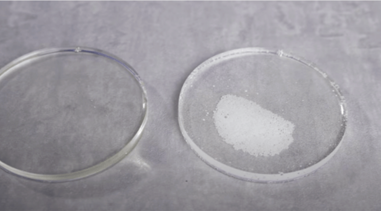 A close-up view of two clear epoxy resin discs on a textured surface, one disc perfectly smooth and the other with a heart-shaped area filled with tiny air bubbles, illustrating the concept of removing epoxy resin bubbles after curing.