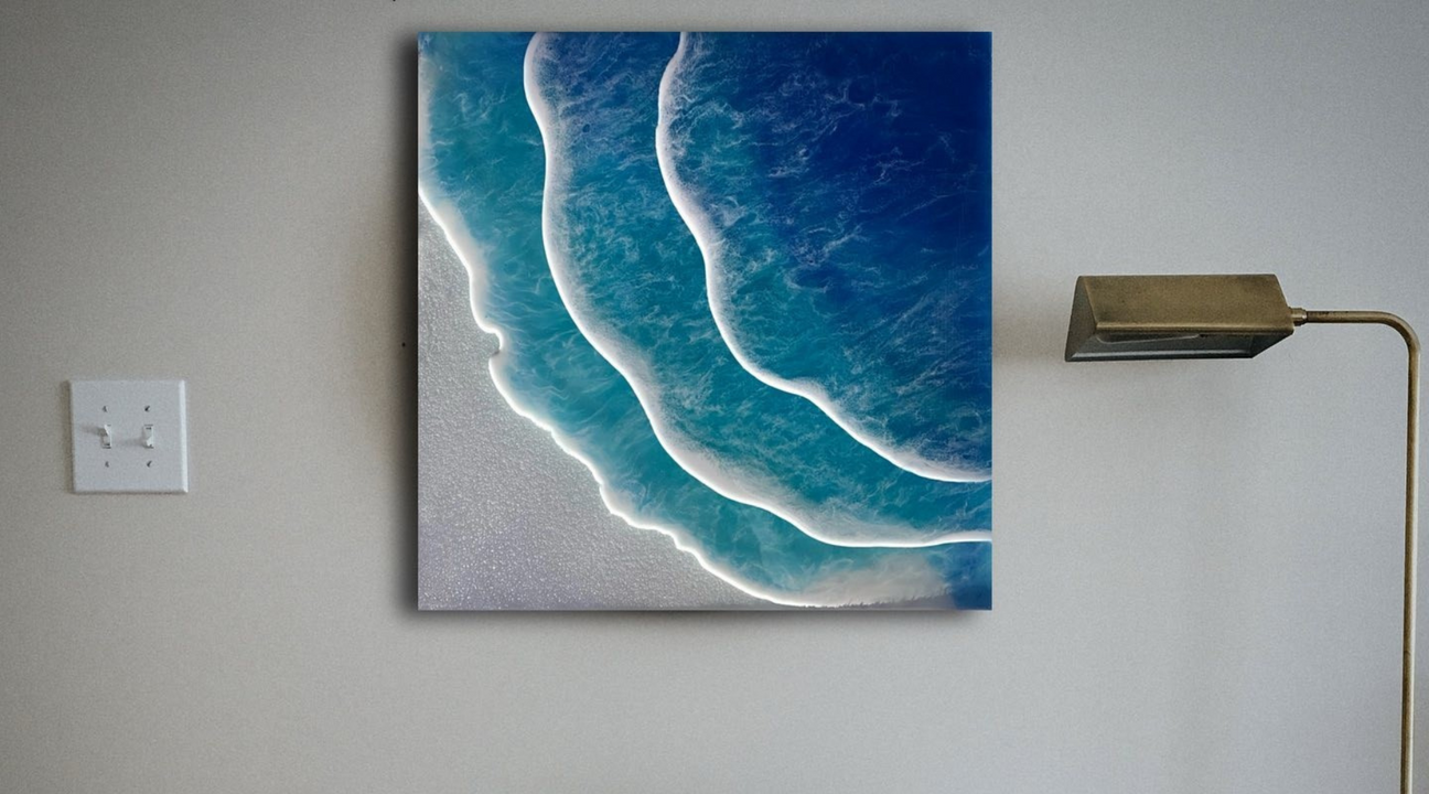 An epoxy resin wall art piece depicting rolling ocean waves with realistic shades of deep blue and white foam, mounted on a grey wall beside a sleek, brass floor lamp.