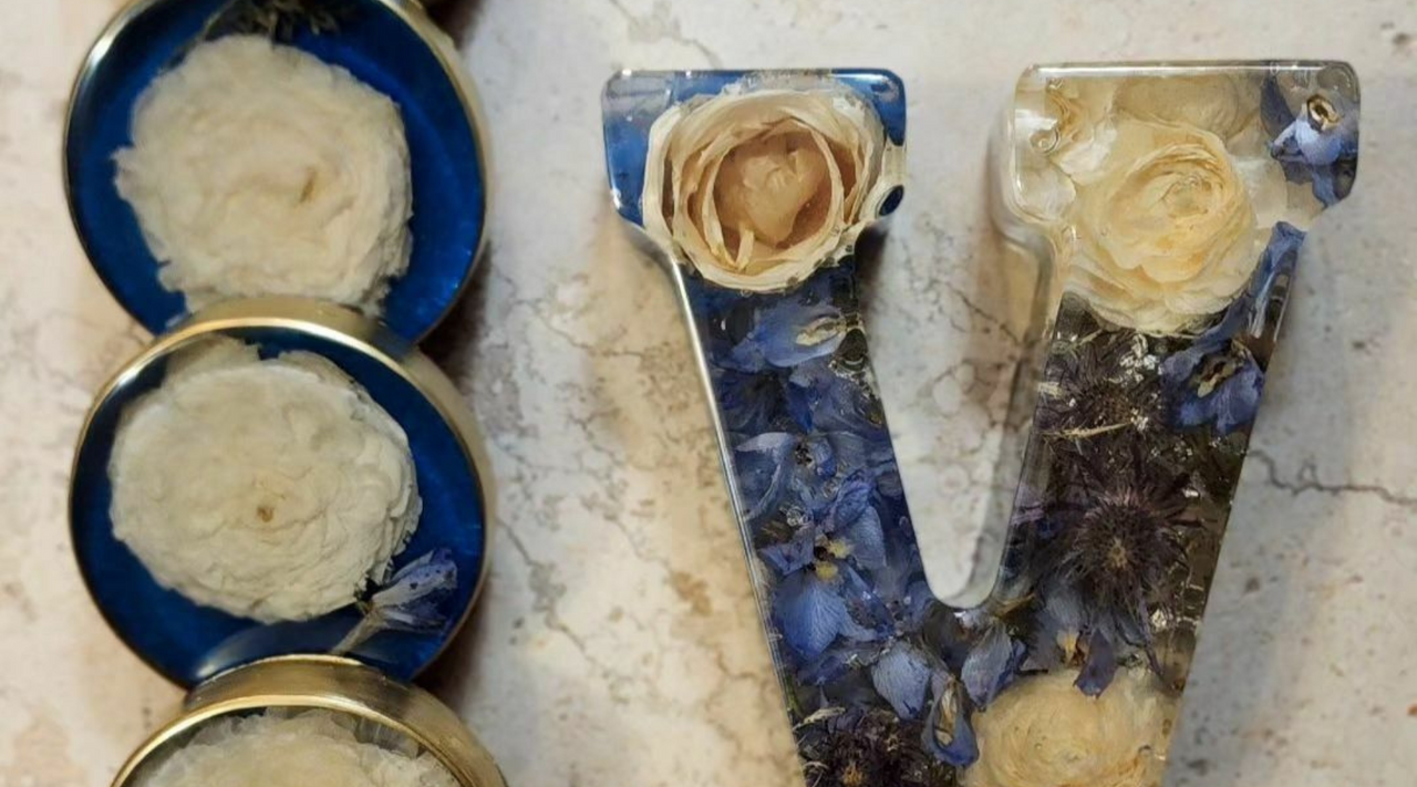 white roses embedded in epoxy resin project of coasters and the letter V sitting on a marble countertop