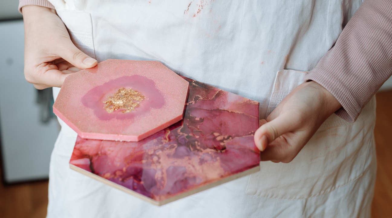 woman holding two pink resin coasters showing how to get bubbles out of resin