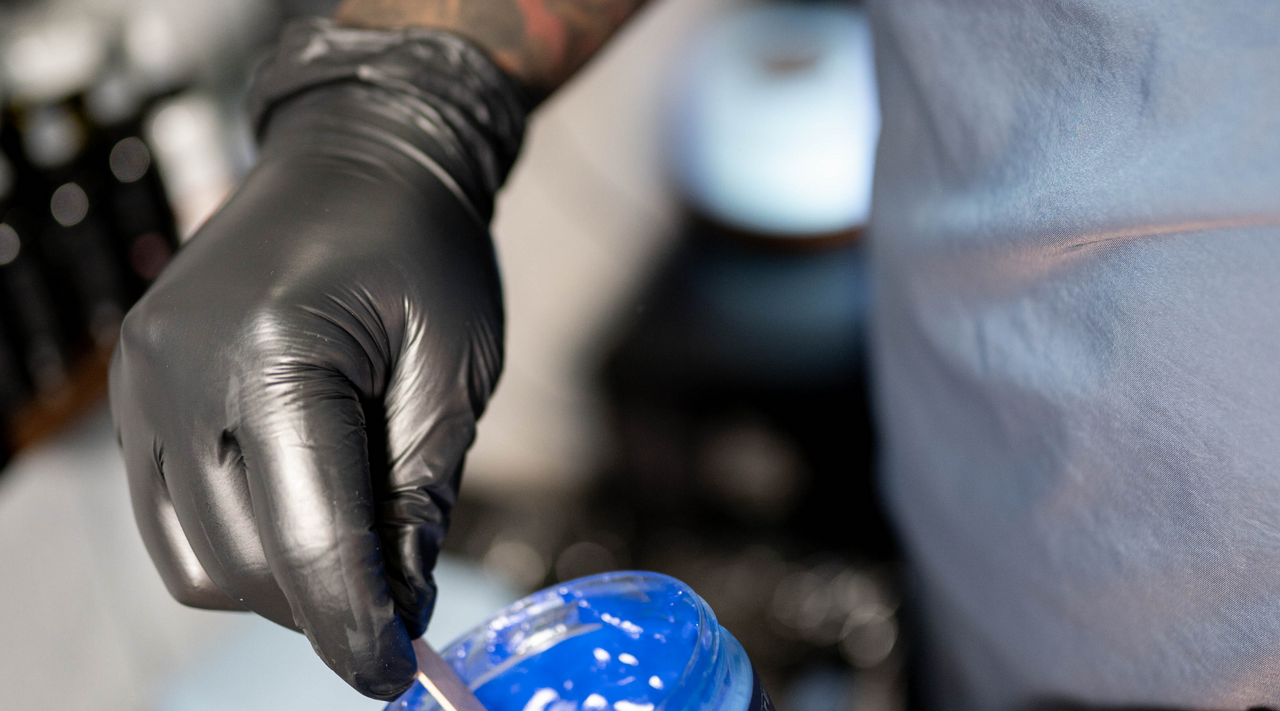 gloved hand stirring blue epoxy resin to help answer the question is epoxy safe?